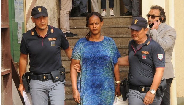 A woman is escorted by Italian police officers in Palermo, Italy, after they arrested people who belonged to an organisation that had smuggled thousands of migrants into Europe from Africa.