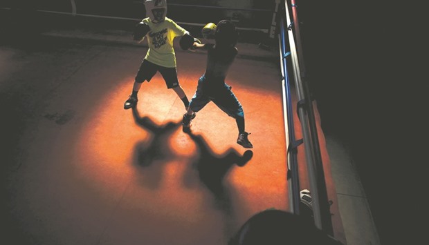 Students sparring at the Louisville TKO Boxing Gymnasium in Louisville, Kentucky. The concrete building in Louisville, Kentucky looks like it might once have been a workshop or possibly a warehouse, but it now holds a boxing ring where heirs to Muhammad Aliu2019s storied legacy are determined to do him proud. A glow of neon and sunshine streaming in from a skylight overhead illuminate the action at the centre of TKO club, where two teens wearing protective helmets and boxing gloves are facing off.