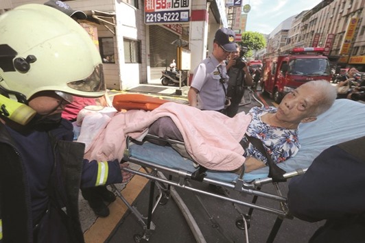 Rescuers transport an elderly person after a fire at a nursing home in New Taipei City yesterday. The fire that tore through the private nursing facility killed six and injured another 28.