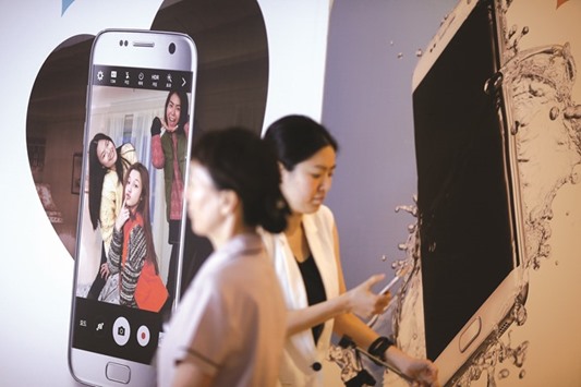 Women walk past an advertisement promoting a Samsung Electronics smartphone at its headquarters in Seoul. The South Korean electronics giant yesterday predicted an  operating profit of 8.1tn won ($7bn) in April-June, up 17% from a year ago.