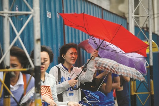 A woman struggles to control her umbrella as she walks in the rain in Manila yesterday.