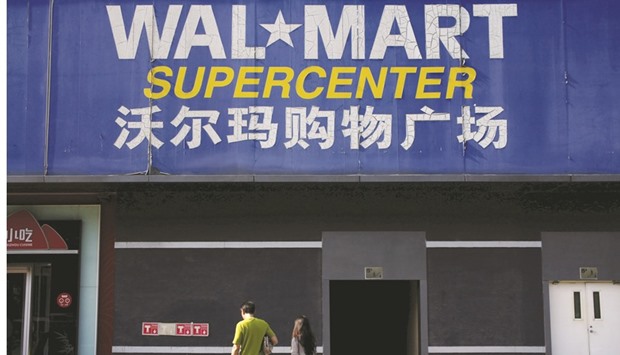 Pedestrians walk past a signboard of Wal-Mart store in Beijing. The US firm said on Thursday it has introduced the new work hour scheduling system in July across its hypermarkets in China, and the majority of its employees supported it.