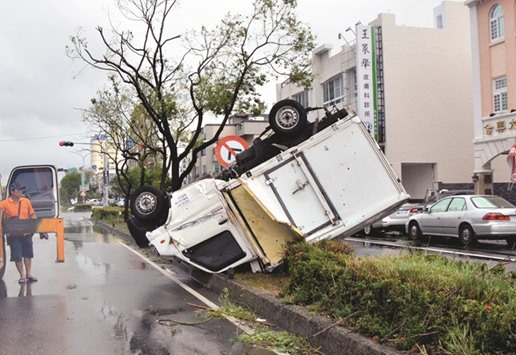 A truck lies upside down on a traffic divider after being blown over by strong winds in the Taiwanese city of Taitung, after Super Typhoon Nepartak passed over the island.