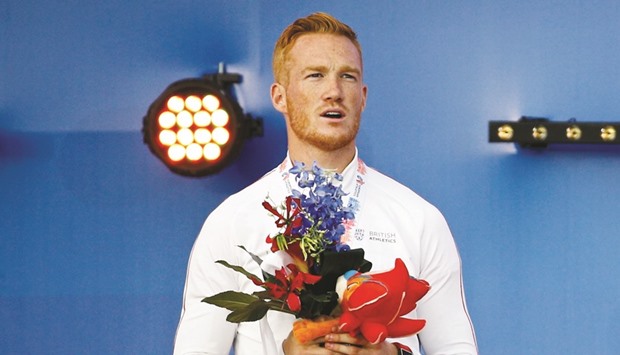 Britainu2019s Greg Rutherford reacts on the podium.
