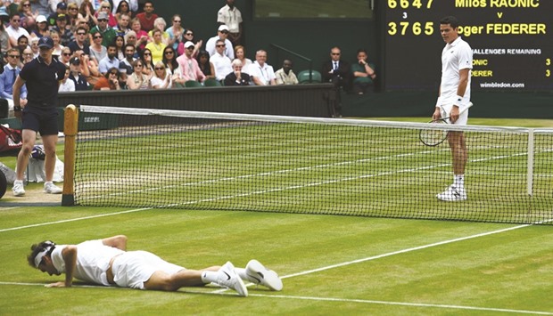 Switzerlandu2019s Roger Federer lies on court after falling while trying to return against Canadau2019s Milos Raonic during their Wimbledon semi-final at The All England Club yesterday. (AFP)