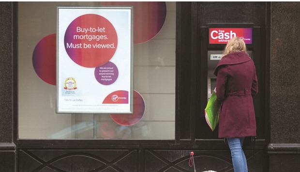 A customer uses an automated teller machine operated by Virgin Money Holdings (UK), outside a bank branch in London. Among challenger banks, shares of Virgin Money, Aldermore, OneSavings Bank and Shawbrook have fallen an average 37% since the UK referendum on June 23.