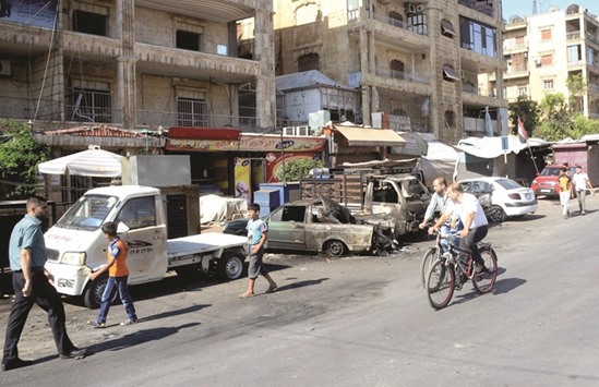 Syrian pass burnt-out vehicles a day after shelling on the regime-held Furqan neighbourhood of Aleppo yesterday.