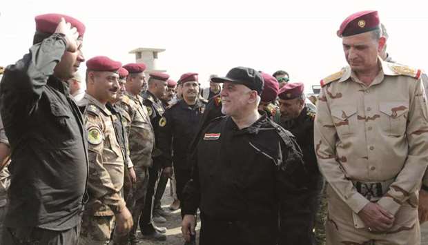 A handout picture released yesterday, shows Iraqi Prime Minister Haider al-Abadi (centre) greeting army officers upon his arrival in Mosul.