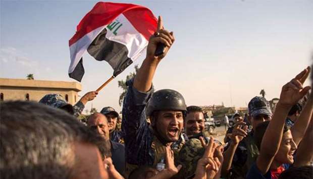 Iraq's federal police members wave the national flag as they celebrate in the Old City of Mosul after the government's announcement of the ,liberation, of the embattled city.