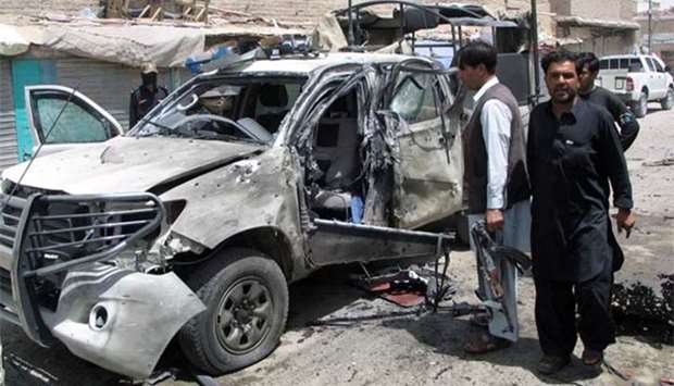 Police and security personnel stand next to a damaged police vehicle after a blast in Chaman, Pakistan on Monday.