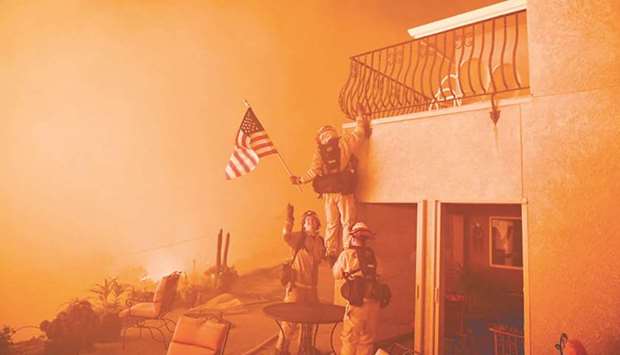 Firefighters save a US flag as flames from the Wall fire close in on a luxury home in Oroville, California.