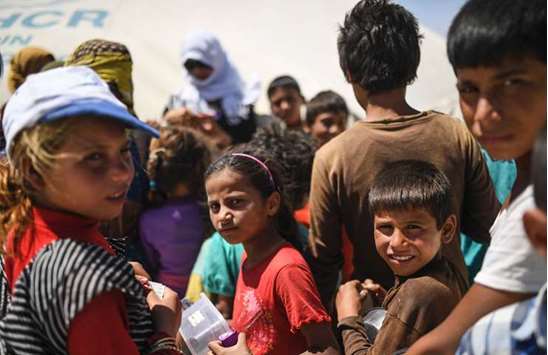Displaced Syrian children who fled the countryside surrounding the Islamic State (IS) groupu2019s stronghold of Raqqa, wait for food distribution at a temporary camp in the village of Ain Issa yesterday.