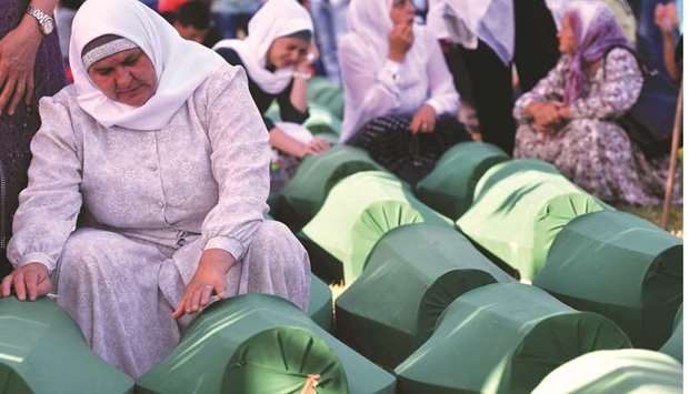 Bosnian women offer prayers near the caskets of 71 victims of the 1995 Srebrenica massacre at the memorial cemetery in the village of Potocari, near the eastern Bosnian town of Srebrenica.