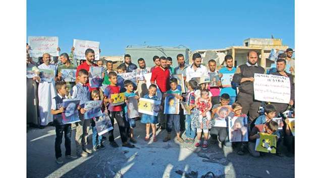 Syrians gather with pictures of victims during a memorial on Wednesday in Khan Sheikhun in the northwestern Syrian Idlib province.