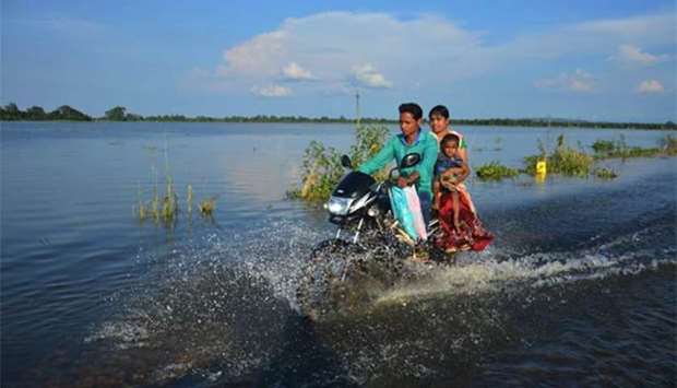 An Indian family travels along a flooded road on a motorbike in Kamrup district in Assam.