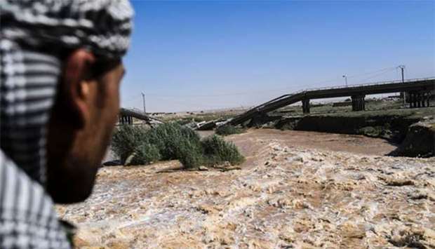 A member of the Syrian Democratic Forces looks at a damaged bridge in eastern Raqa during an offensive to retake the city from Islamic State fighters.