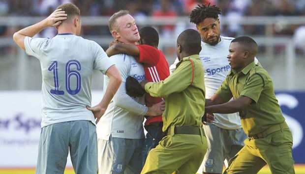 A fan is apprehended by police after running onto the pitch to hug Evertonu2019s Wayne Rooney during a SportsPesa Super Cup final football match against Gor Mahia in Dar-es-Salaam, Tanzania on Thursday. (AFP)