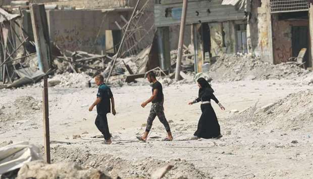 Iraqis walk on a damaged street in west Mosul, a few days after the governmentu2019s announcement of the u201cliberationu201d of the embattled city from Islamic State (IS) group fighters.