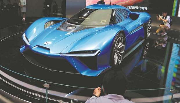 People gather around the Nio EP9 electric car displayed at the Shanghai Auto Show. Keen to combat air pollution, China is planning to set goals for electric and plug-in hybrid cars to make up at least a fifth of Chinese auto sales by 2025, with a staggered system of quotas beginning in 2018.