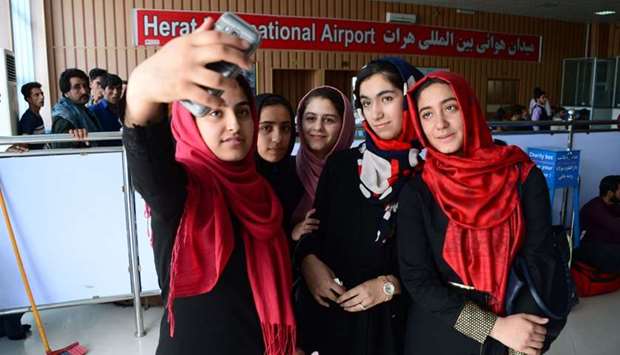 Afghan teenagers from the Afghanistan Robotic House take pictures with a mobile phone at Herat International Airport on July 13, 2017, before embarking for the United States