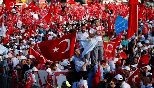 People wave Turkey's national flags as they arrive to attend a ceremony marking the first anniversary of the attempted coup at the Bosphorus Bridge in Istanbul.