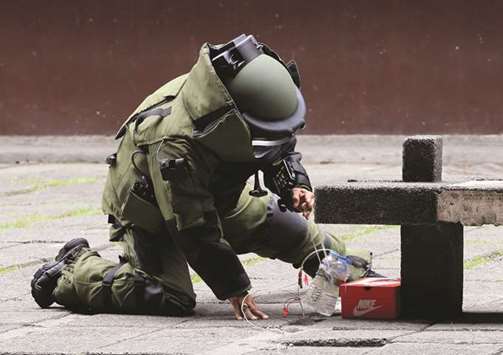 A member of the local Explosives and Ordnance Division wearing a specialised suit tries to install a water diffuser to an improvised explosive device during a bomb drill in a high school courtyard in Tondo, Metro Manila.