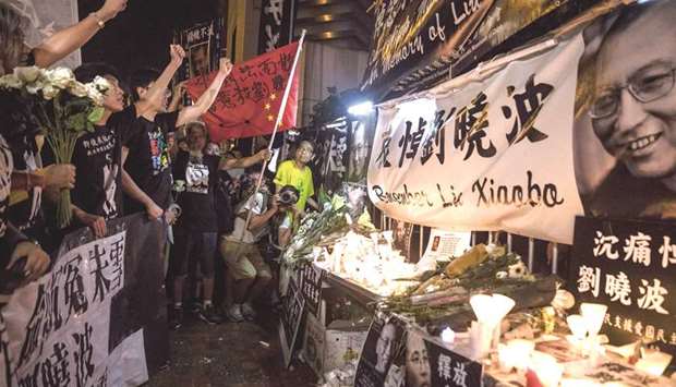 Pro-democracy activists chant slogans in front of a makeshift memorial for the late Chinese Nobel laureate Liu Xiaobo outside the Chinese Liaison Office in Hong Kong yesterday.