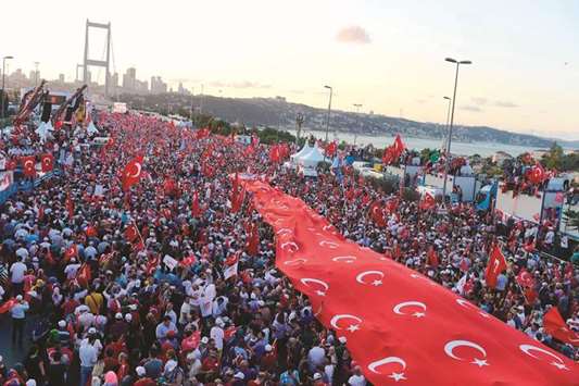 People stand under a collection of Turkish national flags as they gather on the u201cJuly 15 Martyrs Bridgeu201d (Bosphorus Bridge) in Istanbul  yesterday.