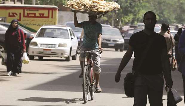 A bakery worker rides a bicycle as he carries bread on his head in Cairo. A fast growing population means that Egypt, the worldu2019s largest wheat importer, will continue to need large amounts of foreign grain.
