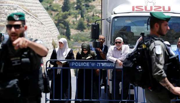 Palestinians stand next to a police barricade as they wait for the compound known to Muslims as Noble Sanctuary and to Jews as Temple Mount to be reopened, in Jerusalem's Old City.