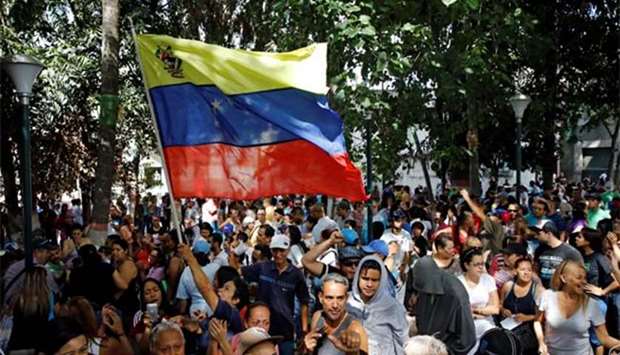 People hold a national flag while gathering at a polling station in Caracas on Sunday.