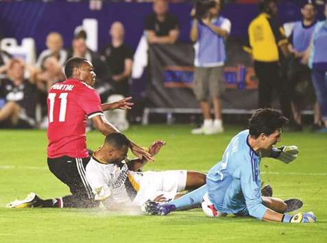 Anthony Martial (left) of Manchester United collides with Ashley Cole of Los Angeles Galaxy as goalkeeper Brian Rowe (right) makes a save during a pre-season friendly match at StubHub Center in Carson, California on Saturday. (AFP)