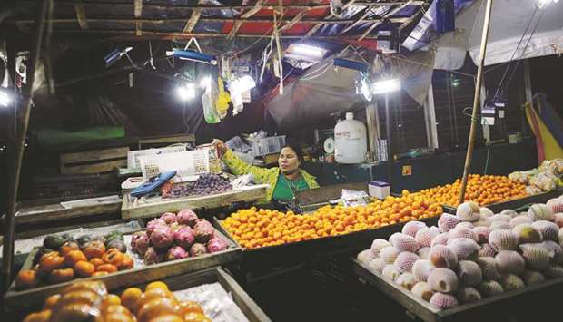 A woman sells fruit at a stall lit with battery powered lamps in Dala township, outside Yangon.
