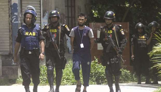 Bangladesh Rapid Action Battalion (RAB) personnel detain a suspected Islamist extremist after he surrendered in Ashulia, some 25kms from Dhaka yesterday. Four suspected Islamist extremists surrendered after a night-long standoff with Bangladeshi police in which they detonated explosives and opened fire outside the capital Dhaka.