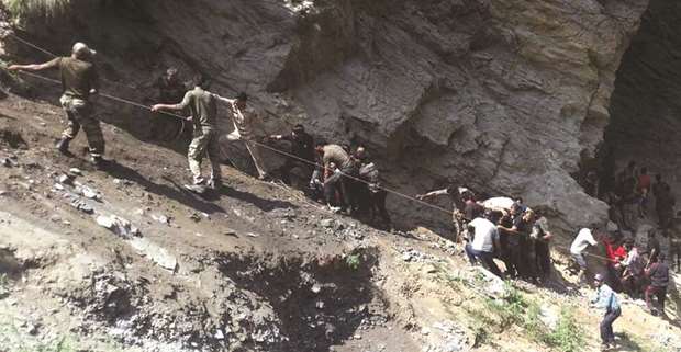 Police personnel and locals carry injured and dead from the site of a bus accident in Ramban district, about 140km from Jammu yesterday.