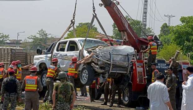 Pakistani officials use a crane to lift a security vehicle at the site of suicide bomb attack in Peshawar