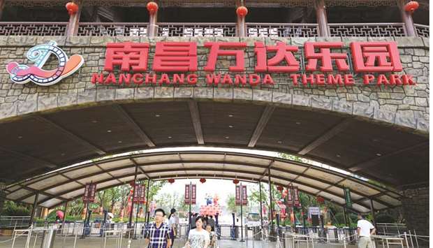 People walk under a logo of Wanda Theme Park in Nanchang, Jiangxi province. Chinau2019s regulators have told banks to stop providing funding for several of Dalian Wanda Groupu2019s overseas acquisitions as Beijing looks to curb the conglomerateu2019s offshore buying spree, sources familiar with the matter said yesterday.
