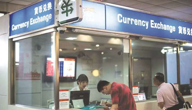 A man changes foreign currency into Chinese yuan at a currency exchange office at Hongqiao airport in Shanghai. The yuan closed up for a sixth day yesterday, the longest run of gains since 2015, amid data showing Chinau2019s economy beat expectations in the second quarter.