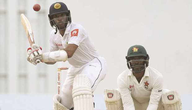 Sri Lankan cricketer Kusal Mendis (L) plays a shot as Zimbabwe wicketkeeper Regis Chakabva looks on during the fourth day of a one-off Test in Colombo.
