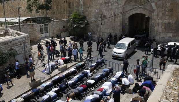 Palestinian Muslim worshippers, who refuse to enter Al-Aqsa mosque compound due to newly-implemented security measures by Israeli authorities which include metal detectors and cameras, pray outside the Lions Gate, a main entrance to Al-Aqsa mosque compound, in Jerusalem's Old City yesterday.