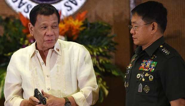 Philippine President Rodrigo Duterte (L) holds a .45 caliber handgun, one of 3,000 units handed over during a ceremonial turn-over to the military, at Malacanang Palace in Manila