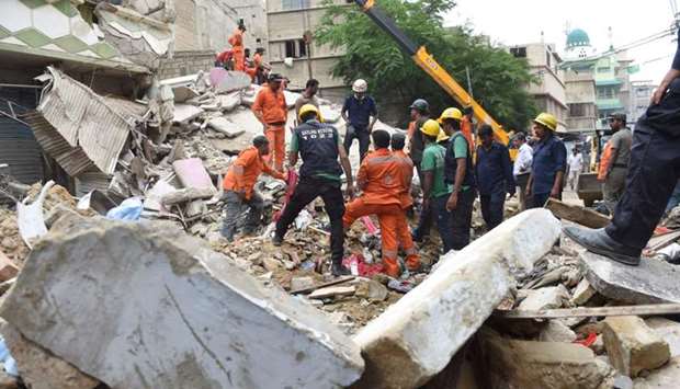 Pakistani rescue workers search for victims as they remove debris after a three story building collapsed at a residential area in Karachi.