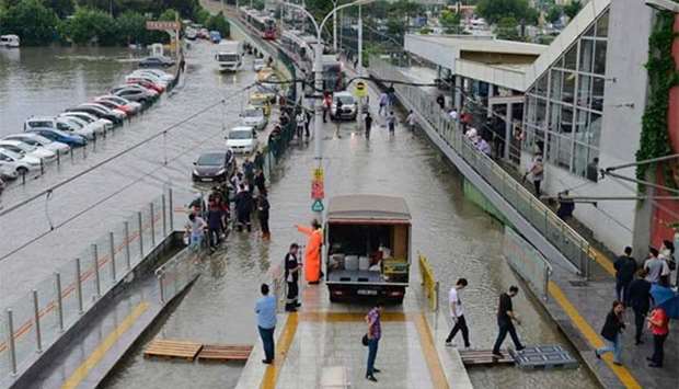 People walk on wood panels to cross a flooded street at the Zeytinburnu metro station in Istanbul on Tuesday following a heavy rainfall.