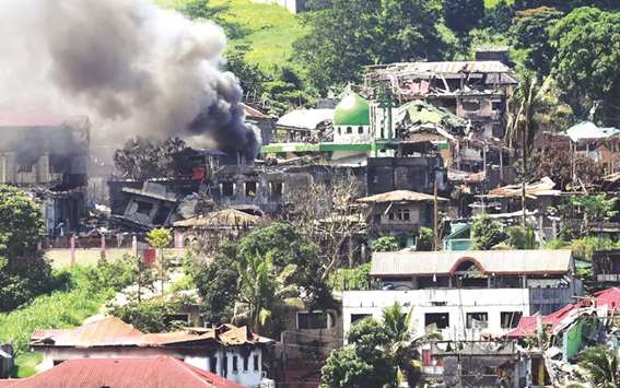 The photo taken on June 26 shows smoke billowing from a burning house after an aerial bombing on militant positions in Marawi, on the southern island of Mindanao. An Islamic finance-backed scheme to rebuild Marawi City should allow reconstruction efforts mindful of the Muslim culture and heritage of the city and would also open channels for monetary support and participation from the Middle East, according to an official.
