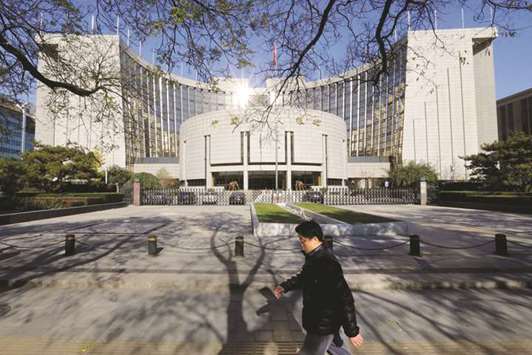 A man walks past the headquarters of the Peopleu2019s Bank of China in Beijing. Chinau2019s President Xi Jinping said that a new Financial Stability and Development Committee will be set up under the State Council, or cabinet, and that the PBoC will take on a bigger role in managing risks in the financial market.
