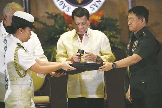 President Rodrigo Duterte holds a .45 calibre handgun, one of 3,000 units handed over during a ceremonial turn-over to the military, at Malacanang Palace in Manila yesterday.