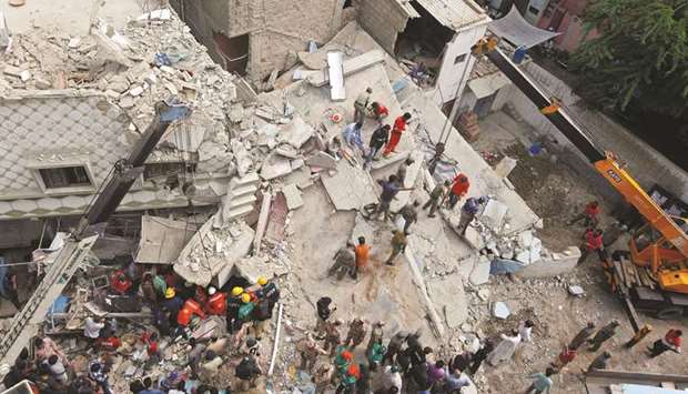 Rescue workers go through the rubble of a three-storey residential building, which collapsed early morning in Karachi yesterday.