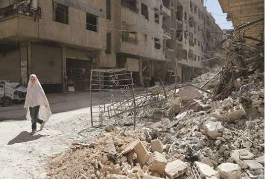  A girl walks past the rubble of a destroyed building down a street in the rebel-held Syrian town of Ayn Tarma, in the Ghouta area.
