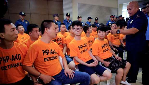 Philippine National Police (PNP) Chief Ronald Dela Rosa (R) confronts some of the 43 arrested foreigners, mostly Chinese nationals, for kidnapping a Singaporean woman at a casino resort in the capital, during a presentation inside the PNP Headquarters in Quezon City, Metro Manila, Philippines