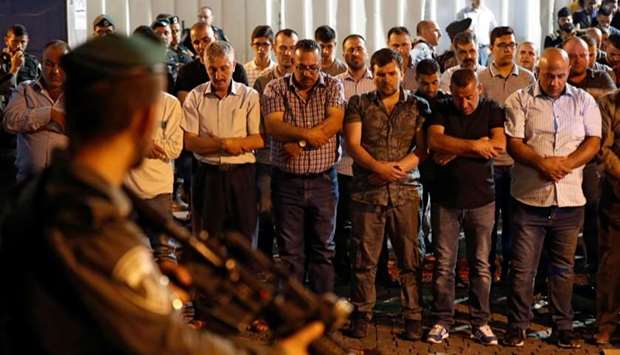 Israeli security forces stand guard in front of Palestinian Muslim worshippers praying outside Lions Gate, a main entrance to the Al-Aqsa mosque compound in Jerusalem's Old City.